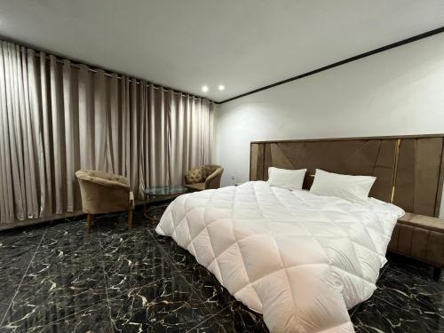 a bedroom with a large white bed and two chairs at Rafsal A Countryside Cottage in Skardu
