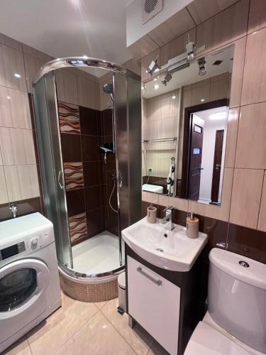 W łazience znajduje się prysznic, umywalka i pralka. w obiekcie Apartament z widokiem na morze w mieście Gdynia