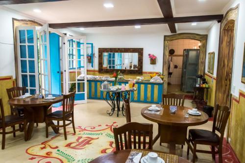 a restaurant with tables and chairs and a kitchen at Pousada Richard Rothe in Tiradentes