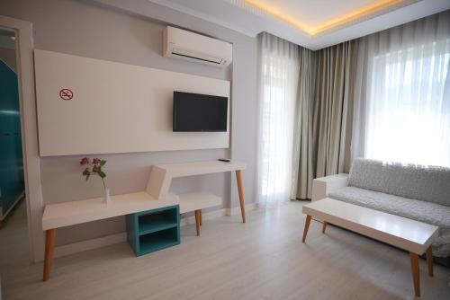 een woonkamer met een bank en een tv bij Sea Front Pansiyon in Antalya