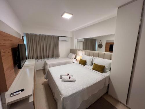 a hotel room with two beds and a flat screen tv at Beach Place - Apartamento 03 decorado a 100m da Praia do Cumbuco in Cumbuco