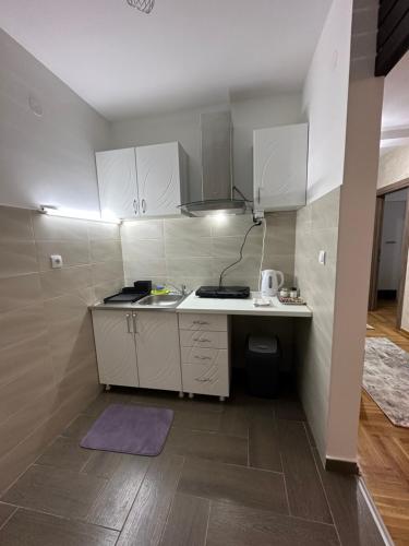 - une petite cuisine avec des placards blancs et un tapis violet dans l'établissement Port 3, à Belgrade