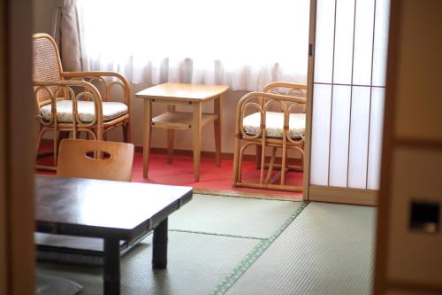 a room with chairs and a table and a window at Tsukasaya Ryokan in Tsuruoka
