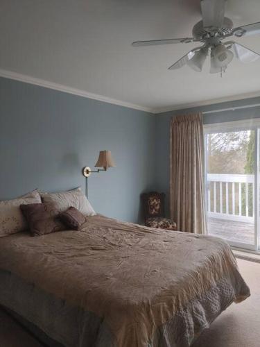 a bedroom with a bed with a ceiling fan and a window at Vinegar Hill Airbnb in Bridgetown