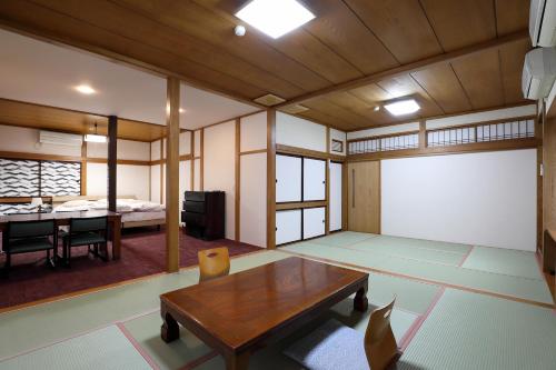 Zimmer mit einem Tisch und einem Zimmer mit einem Bett in der Unterkunft Tsukasaya Ryokan in Tsuruoka