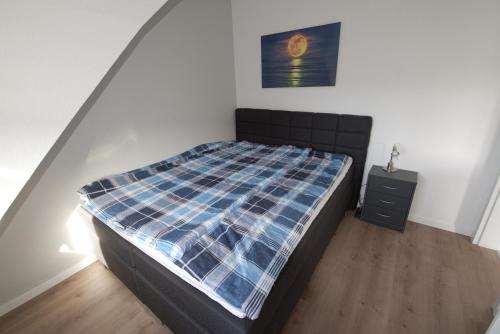 a bedroom with a bed with a checkered blanket at Deichläufer in Dorum Neufeld