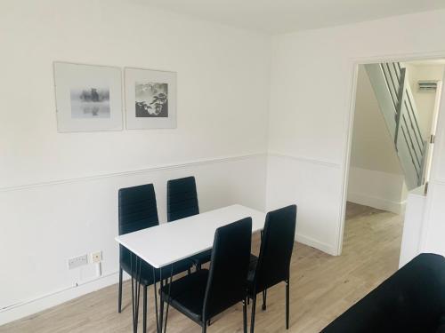 a dining room with a white table and black chairs at Greenshaw 3 Bedroom Terrace in Brentwood