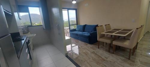 a living room with a table and a blue couch at Apartamento clube próximo à praia in Caraguatatuba