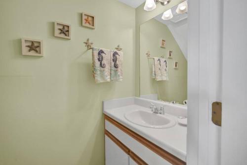 La salle de bains blanche est pourvue d'un lavabo et d'un miroir. dans l'établissement Sandcastles and Sunshine - Gulf Highlands Beach Resort, à Panama City Beach