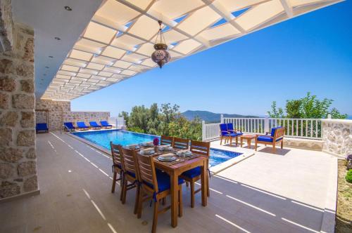 eine Terrasse mit einem Tisch und Stühlen sowie einem Pool in der Unterkunft Villa Karmen in Kaş
