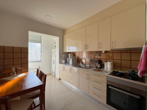 uma cozinha com armários brancos e uma mesa em Guest House “Casa da avó Tina” no Barreiro