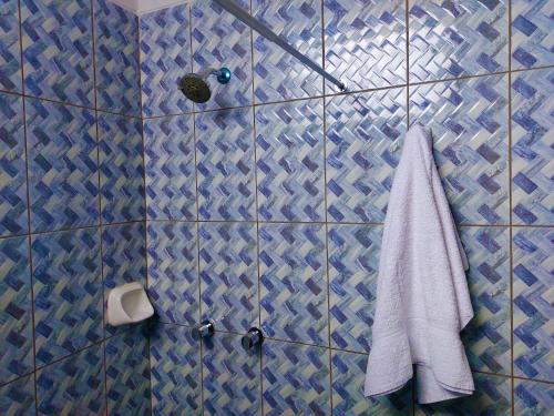 a blue tiled bathroom with a towel and a shower at Kasanty House in Paracas