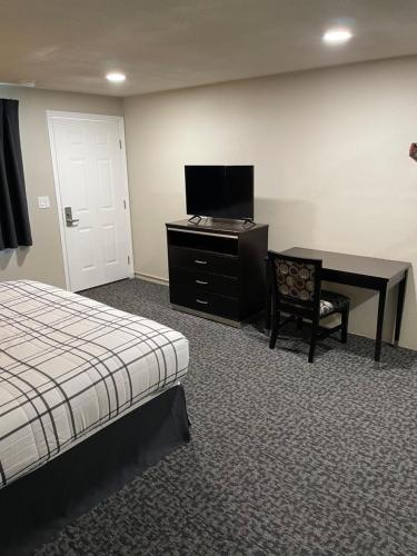 Cette chambre comprend un lit, un bureau et une télévision. dans l'établissement Royal Inn Eugene- Airport, à Eugene