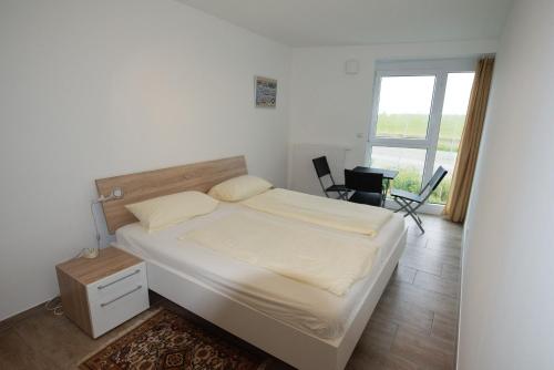 a white bedroom with a bed and a window at de Rootbost in Neufeld