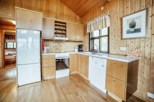 a kitchen with a white refrigerator and wooden walls at Minniborgir Cabins in Minni-Borg