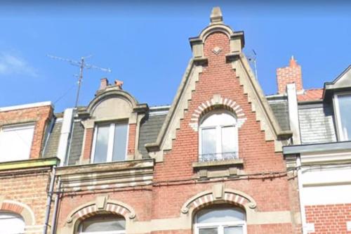 un bâtiment en brique avec une tour d'horloge en haut. dans l'établissement Le Beffroi : appartement cosy en cœur de ville, à Armentières