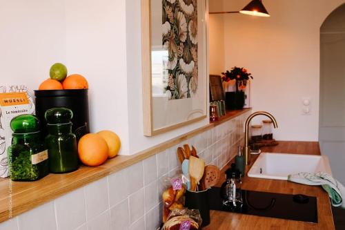 eine Küchentheke mit einer Spüle sowie Obst und Gemüse in der Unterkunft Le Beffroi : appartement cosy en cœur de ville in Armentières