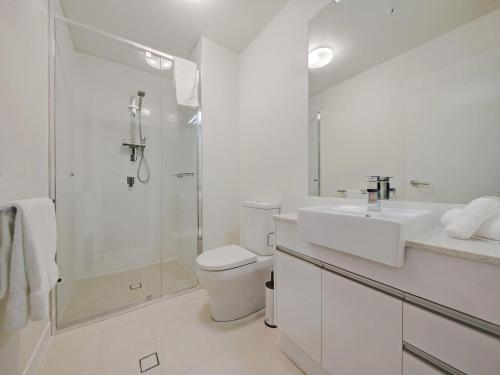 a white bathroom with a sink and a shower at Link Portside Wharf Apartment Hotel in Brisbane