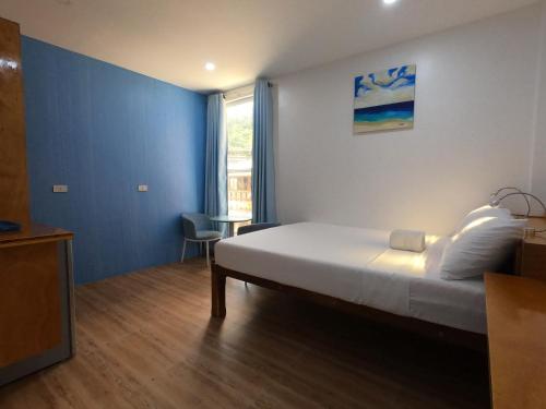 a bedroom with a large bed with a blue wall at The Beach House in El Nido