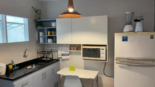 uma cozinha com um frigorífico branco e uma pequena mesa em Loft para temporada em Cabo Frio