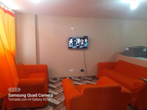 uma sala de espera com cadeiras laranja e uma televisão em Kely2 Tercer Piso em Lima