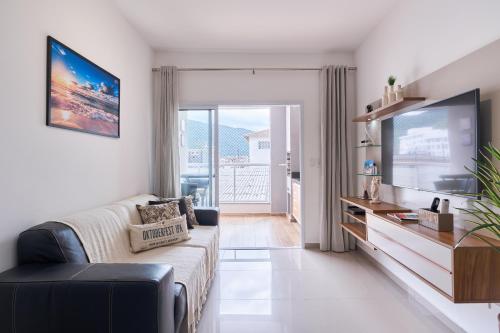 uma sala de estar com um sofá e uma televisão em 2 QUARTOS com Churrasqueira na Varanda, Piscina, Garagem interna, WiFi 500mbps, Ar Condicionado e Telas de Proteção em Ubatuba