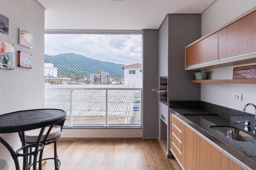 a kitchen with a table and a large window at 2 QUARTOS com Churrasqueira na Varanda, Piscina, Garagem interna, WiFi 500mbps, Ar Condicionado e Telas de Proteção in Ubatuba