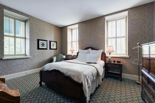um quarto com uma cama, uma secretária e janelas em Nicollet Island Inn em Minneapolis