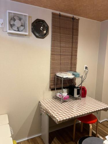 Zimmer mit einem Tisch und einem Fenster mit einem Ventilator in der Unterkunft 雅 in Nishinotōindōri