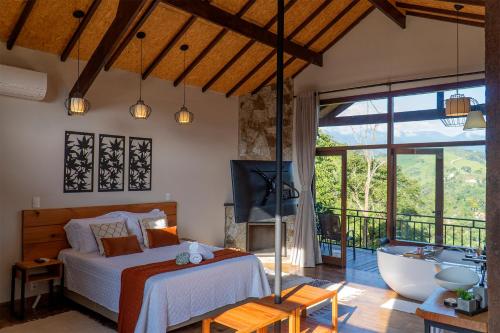 a bedroom with a bed and a tub and a television at Monte Mauá Chalés in Visconde De Maua