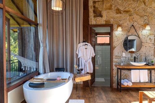 a bathroom with a tub and a stone wall at Monte Mauá Chalés in Visconde De Maua