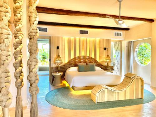 a bedroom with a bed and a couch and a chair at Hotel Shibari - Restaurant & Cenote Club in Tulum