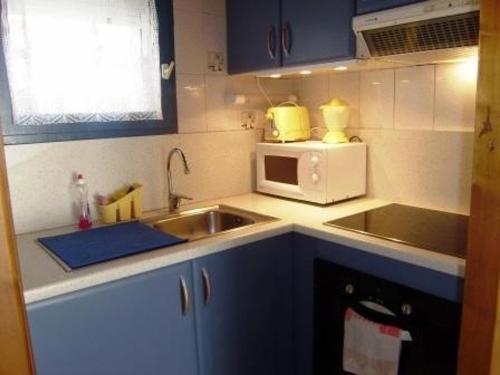 une petite cuisine avec un évier et un micro-ondes dans l'établissement Appartement T3 chaleureux, 7 pers, cheminée, animaux admis, WiFi, proche commerces - FR-1-402-87, à Esquièze - Sère
