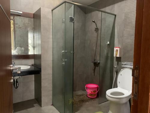 a bathroom with a glass shower with a toilet and a sink at Villa Qfa Syariah in Lembang