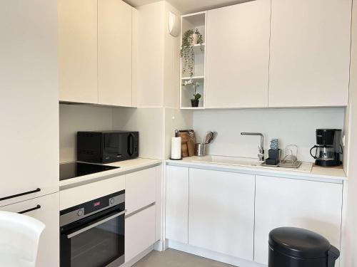 une cuisine blanche avec des armoires blanches et un micro-ondes dans l'établissement **Sainte-Maxime: Appart Neuf 2 Pièces, Terrasse, Clim, 4 Couchages** - FR-1-226-519, à Sainte-Maxime