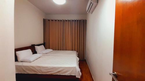 um pequeno quarto com uma cama com lençóis brancos e almofadas em LAKNA HOUSE em Colombo