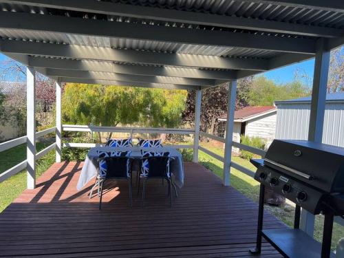 a table and chairs on a deck with a grill at Cosy Eildon Getaway in Eildon