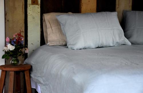 a bed with white sheets and pillows next to a table at On Bell Glamping in Belford