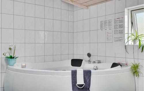 a white bath tub in a white tiled bathroom at Holiday Home Lyngen in Søndervig