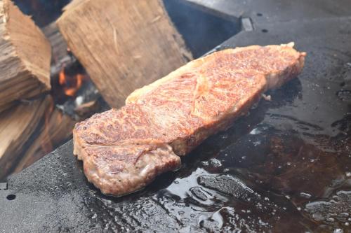 a piece of meat cooking on a grill at Roots inawashiro Lake Area in Sekiwaki