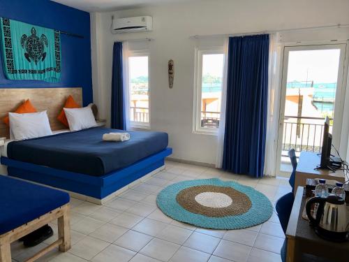 a blue bedroom with a bed and a living room at Blue Ocean Hotel in Labuan Bajo