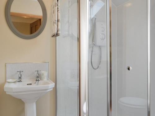a bathroom with a sink and a shower with a mirror at Kilbride Beach Cottage in Pollachar