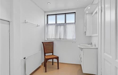een stoel in een badkamer met een wastafel en een raam bij 1 Bedroom Cozy Apartment In Svendborg in Svendborg