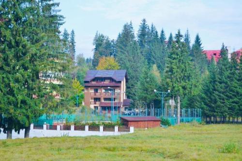 a large building in the middle of a field with trees at Pensiunea Zimbrul in Poiana Brasov