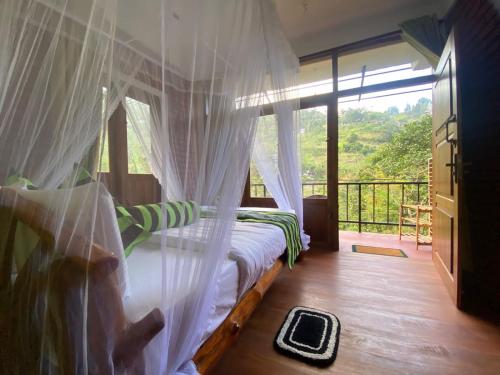 a bedroom with a bed with a canopy and a window at NatureWoodland in Ella