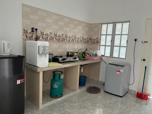 a kitchen with a counter with a microwave and a refrigerator at Safiyya Homestay in Pantai Cenang