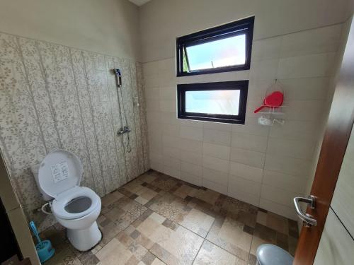 a bathroom with a toilet and a window at Villa Otti, Batu in Songgoriti