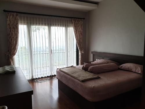 a bedroom with a bed and a large window at Villa Otti, Batu in Songgoriti