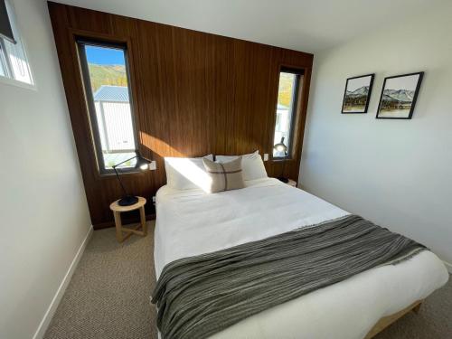 um quarto com uma cama grande e 2 janelas em Abodo Alpine Eco Villa (Spa) em Cardrona