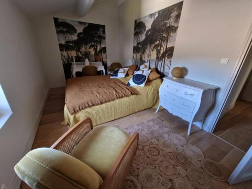une chambre avec un lit, une commode et une chaise dans l'établissement MAISON BELLEVUE DE SAGRIES, à Sagriès